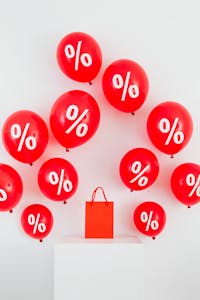 Red balloons with percentage symbols and a shopping bag on white background.